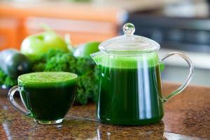 Glass cup of green vegetable juice on kitchen counter