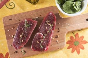 Raw beef tenderloin with spices over a wooden table photo