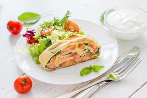 pastel de milhojas con salmón y espinacas, servido en plato blanco foto