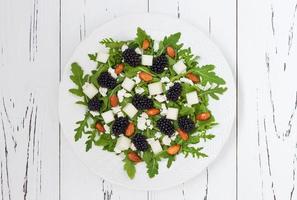 Green salad with arugula, melon, blackberries, almonds and feta cheese