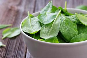 Fresh young leaves of spinach in bowl photo