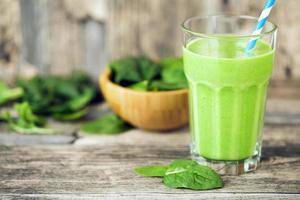 green smoothie juice on wooden table with spinach