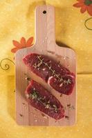 Raw beef tenderloin with spices over wooden table