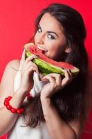 beautiful young woman holding watermelon against red background photo
