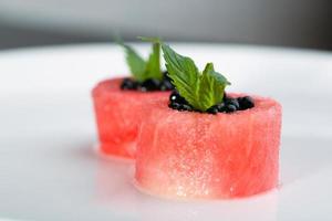 Dish of watermelon with black caviar on a white plate