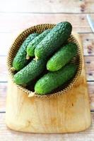 Cucumbers in a basket on chopping board photo