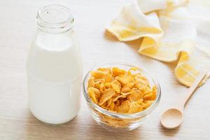Bowl of cornflake and milk bottle on table photo