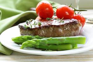 grilled meat beef steak with vegetable garnish (asparagus and tomatoes) photo