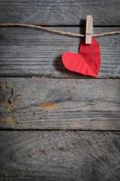 Red heart hanging on the clothesline. On old wood background. photo