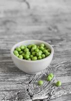 green peas in a white bowl on a  wooden background