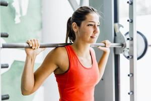 Young beautiful woman lifting weights in a gym photo