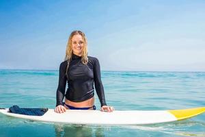 Woman with a surfboard smiling at camera
