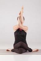 joven hermosa yoga posando sobre fondo gris foto