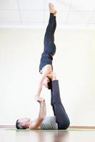 hombre y mujer haciendo acro yoga o yoga par interior foto