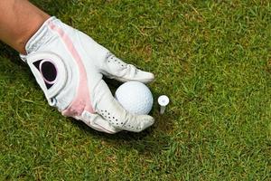 Gloved hand placing golf ball on tee