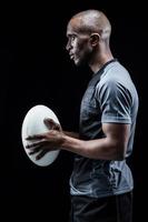 Profile view of confident sportsman holding rugby ball photo