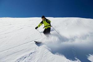 Alpine skier on piste, skiing downhill photo