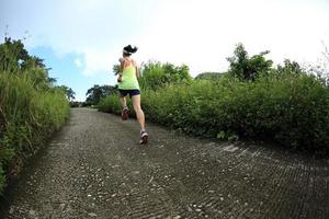 corredor de mujer joven fitness correr por sendero de montaña foto