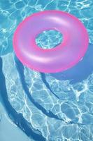 anillo rosa flotando en una piscina azul foto
