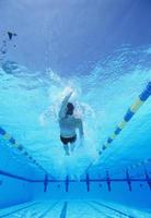 Underwater shot young male athlete doing backstroke in swimming pool photo