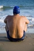 Nadador sentado en la playa.