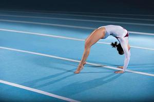 A young female gymnast posing in a bridge on a blue mat photo