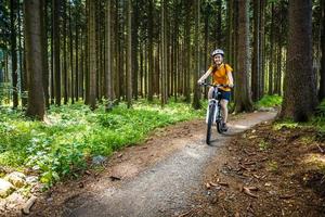 niña montando bicicleta en senderos del bosque foto