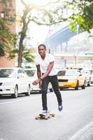 Chico negro patinando con longboard en la carretera foto