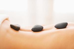 closeup on young woman receiving hot stone massage photo