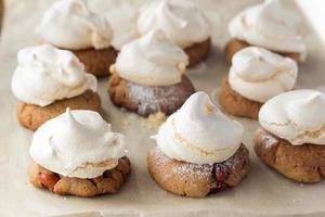 Shortbread cookies with peanut and meringues on cooking paper photo