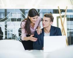 Young businessman with female colleague discussing over laptop at table photo