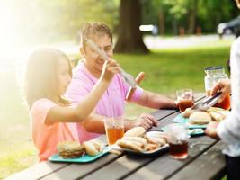 father and daughter eating together at barbecue cookout photo