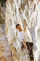 Rock climber climbing up a cliff photo