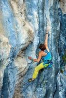 Rock climber climbing up a cliff photo