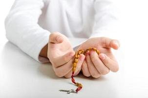 Child hands offer wooden rosary beads