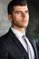 Young businessman near a office building wearing black suit photo
