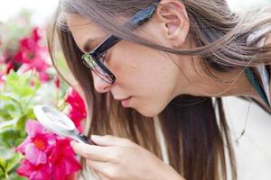 young female gardener monitors health of flowers photo