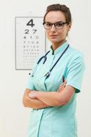 Confianza optometrista femenina de pie con los brazos cruzados foto