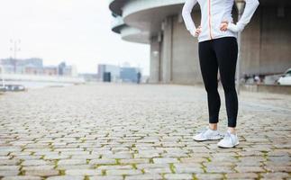 Fitness female standing on sidewalk in city