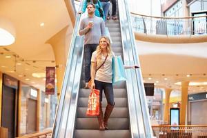Compradora femenina en escaleras mecánicas en el centro comercial foto