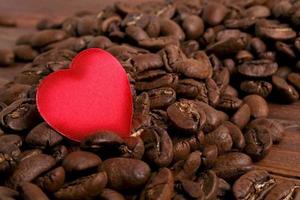 granos de café y corazón rojo sobre fondo de madera