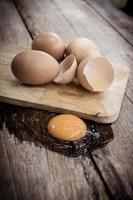 Broken egg on a wooden cutting board on wooden background. photo