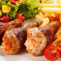 Roasted chicken drumsticks, French fries and vegetables photo
