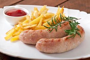 Chicken sausages grilled with a side dish of french fries photo