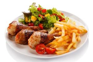 Roasted chicken drumsticks, French fries and vegetables photo