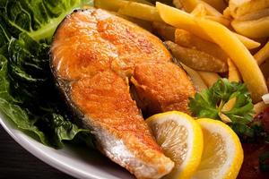 Roasted salmon, French fries and vegetables photo