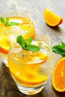 bebidas frías con hielo y menta. cóctel de naranja en rústico foto