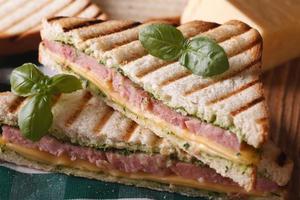 Grilled sandwich with ham, cheese and basil closeup