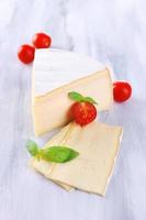 sabroso queso camembert con tomate y albahaca, sobre mesa de madera