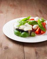 fish baked with mozzarella and salad on a white plate